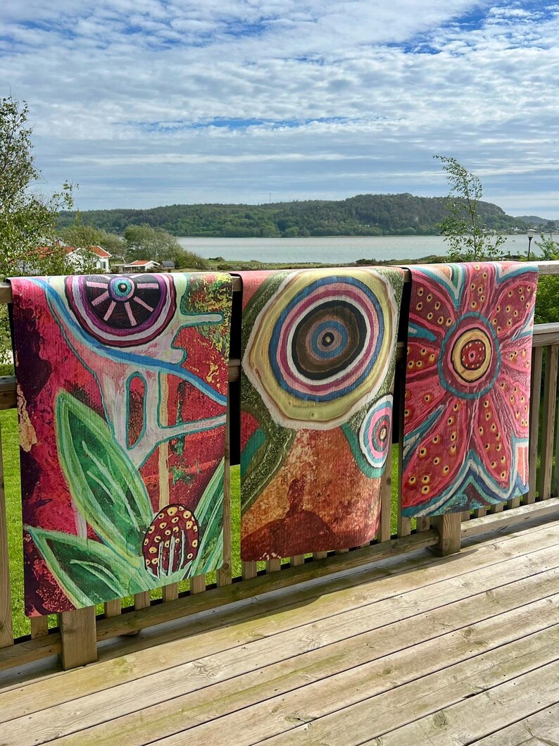 May include: Three rectangular fabric panels featuring vibrant, abstract floral and circular patterns in shades of red, pink, green, and blue. Each panel displays distinct, hand-drawn style motifs, including large petals, concentric circles, and organic shapes.