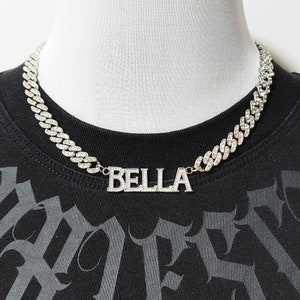 Puede incluir: Un collar de cadena de plata con un colgante de plata que dice "BELLA" en pedrería.