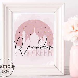 May include: A printable art print with a pink watercolor background and gold stars. The print features a silhouette of a mosque with the text "Ramadan Kareem" in black calligraphy.