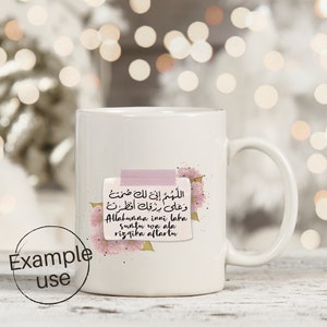 May include: White ceramic mug with a pink floral design and a pink sticky note with Arabic text that reads "Allahumma inni laka suntu wa ala rizqika aftartu".