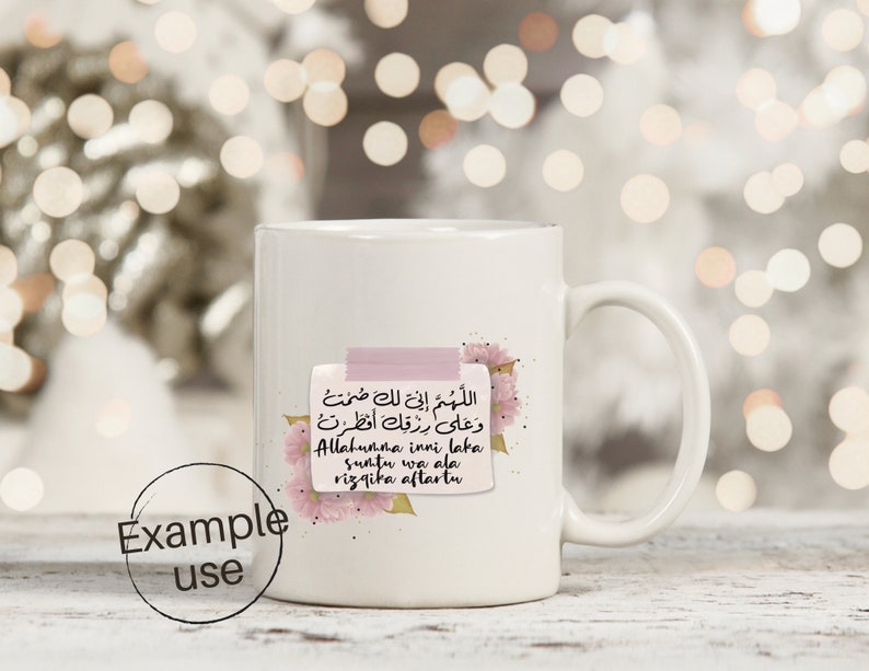 May include: White ceramic mug with a pink floral design and a pink sticky note with Arabic text that reads "Allahumma inni laka suntu wa ala rizqika aftartu".
