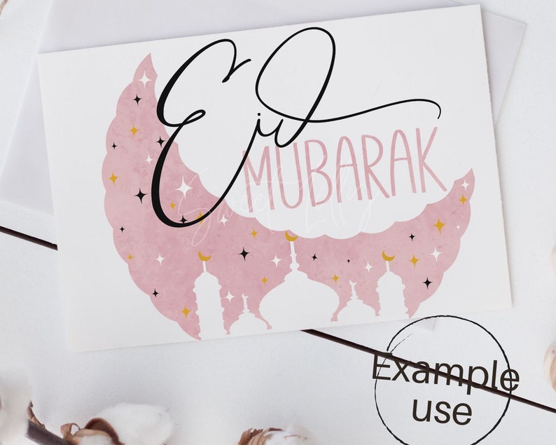 May include: A pink and white card with the text "Eid Mubarak" in black cursive script. The background features a pink crescent moon with gold stars and white silhouettes of mosques.