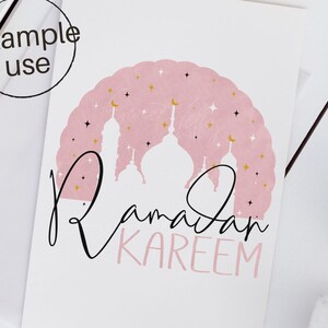 May include: Pink and gold Ramadan Kareem greeting card with a silhouette of a mosque and stars.