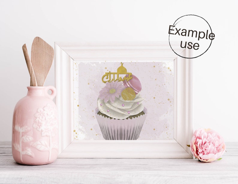 May include: A white cupcake with pink and gold frosting and a gold mosque topper. The cupcake is decorated with pink macarons, gold sprinkles, and a pink flower. The background is a light pink watercolor wash with gold glitter.