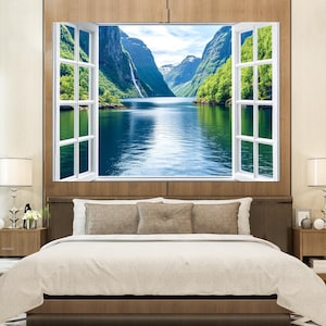 May include: A white window frame with a view of a lake and mountains. The window is open and the view is framed by the window. The lake is blue and the mountains are green.
