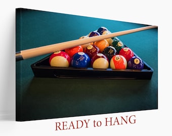 Op de afbeelding: Een groene pooltafel met een driehoek van biljartballen en een biljartkeu. De ballen zijn in een driehoekige vorm gerangschikt en omvatten de nummers 1 tot en met 15. De keu ligt op de tafel naast de ballen. De tekst "READY to HANG" is onder de afbeelding gedrukt.