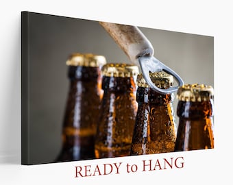 May include: A canvas print featuring four brown beer bottles with gold caps, condensation, and an opener. The text "READY to HANG" is printed in a dark red color at the bottom of the image.