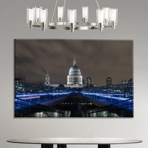 Può includere: Stampa su tela della Cattedrale di St. Paul a Londra di notte, con un ponte con luci al neon blu in primo piano. Un lampadario moderno è appeso sopra la stampa.