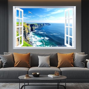 Puede incluir: Un marco de ventana blanco con vista a un acantilado rocoso que domina un océano azul con olas blancas. La ventana está abierta y la vista está enmarcada por la ventana.