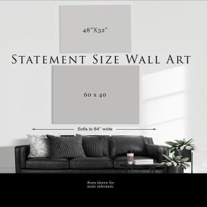 a statement size wall art, which is 60 x 40 inches wide. The artwork is displayed on a wall, and there is a black and white couch in the foreground.