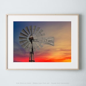 May include: A vintage windmill with a faded sign that reads "HAS A" stands against a vibrant sunset sky with shades of orange, pink, and purple.