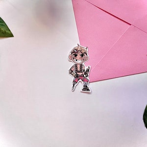 May include: A cartoon sticker of a character with blonde hair, wearing goggles and a red and black outfit. The character is holding a gun and has a mischievous expression.