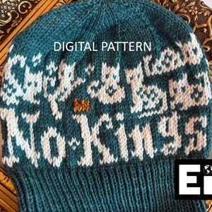 May include: A teal knit hat with white and orange accents. The hat features the words "No Kings" in white, with a pattern above. The text "DIGITAL PATTERN" is at the top. The hat is displayed on a gold-colored frame.