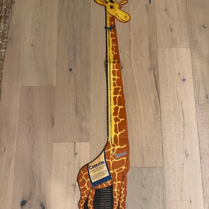 May include: A tall, giraffe-shaped height chart with a yellow and brown spotted design. The chart features a measurement scale in inches and a blue and white label that reads "Cerevim".