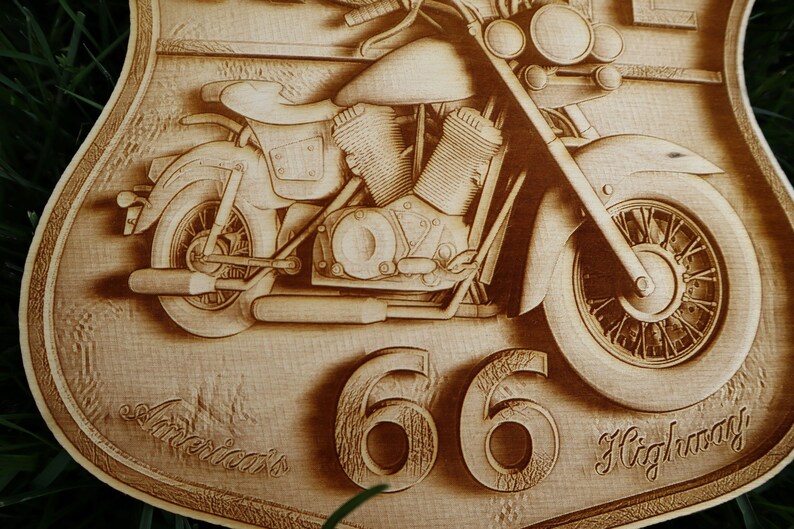 May include: A wooden sign with a carved image of a motorcycle. The sign is shaped like a shield and has the text "America's Highway 66" on it.