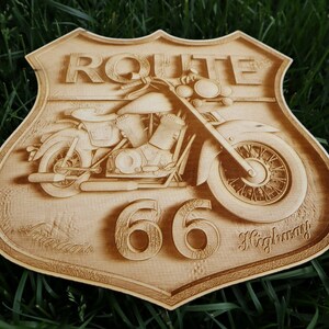 May include: A wooden sign with a vintage motorcycle design. The sign is shaped like a shield and has the text "ROUTE 66 Highway" on it.