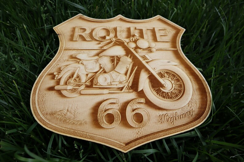 May include: A wooden sign with a vintage motorcycle design. The sign is shaped like a shield and has the text "ROUTE 66 Highway" on it.