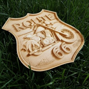 May include: A wooden sign with a vintage motorcycle design and the text "ROUTE 66" in raised letters. The sign is shaped like a shield and has a distressed, weathered look.
