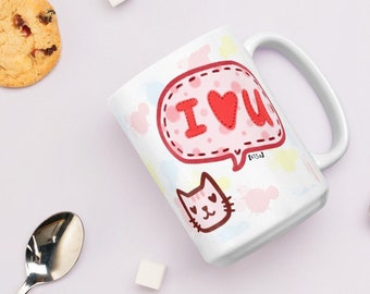 May include: White ceramic mug with a pink and red cartoon design. The design features a speech bubble with the text "I love you" and a pink cat with red hearts for eyes.
