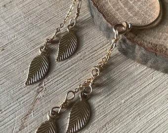 May include: Gold hoop earrings with a dangling chain and three leaf charms.