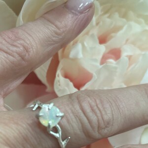 May include: A silver ring with a white opal gemstone set in a branch design.