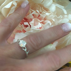 May include: A silver ring with a white opal stone set in a branch design.