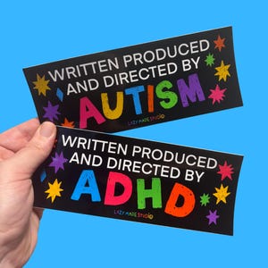 May include: Two black rectangular stickers with the text "WRITTEN PRODUCED AND DIRECTED BY AUTISM" and "WRITTEN PRODUCED AND DIRECTED BY ADHD" in colorful letters. The stickers have star and diamond accents and the words "LAZY MADE STUDIO" at the bottom.