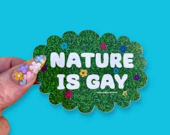 May include: A green and white sticker with a cloud-like shape. The sticker has a green grass background with colorful flowers and the text "NATURE IS GAY".