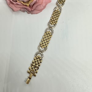 Könnte beinhalten: Ein gold- und silberfarbenes Armband mit einem Kettenglieddesign und klaren Steinen. Das Armband hat einen Verschluss.