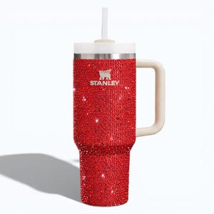 Puede incluir: Un vaso Stanley rojo con pedrer&iacute;a, con asa, tapa y pajita blancas. El vaso tiene el logotipo de Stanley en plata. El exterior rojo est&aacute; cubierto de peque&ntilde;os adornos brillantes. El vaso est&aacute; dise&ntilde;ado para contener aproximadamente 1,2 litros.