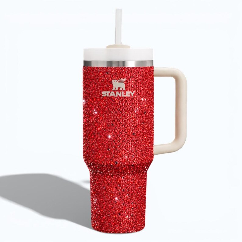 Puede incluir: Un vaso Stanley rojo con pedrer&iacute;a, con asa, tapa y pajita blancas. El vaso tiene el logotipo de Stanley en plata. El exterior rojo est&aacute; cubierto de peque&ntilde;os adornos brillantes. El vaso est&aacute; dise&ntilde;ado para contener aproximadamente 1,2 litros.