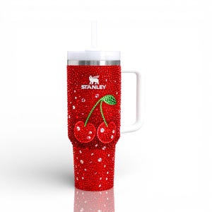 K&ouml;nnte beinhalten: Roter Stanley-Becher mit wei&szlig;em Griff und Strohhalm. Der Becher ist mit roten Strasssteinen bedeckt und zeigt ein Kirschdesign. Das Stanley-Logo ist sichtbar. Ein dekorativer und funktionaler Trinkartikel.