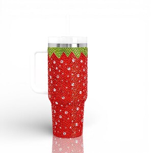 May include: A red tumbler with a white handle and straw, adorned with red and clear rhinestones. The top section is green, resembling a strawberry. The tumbler is designed to hold cold beverages.