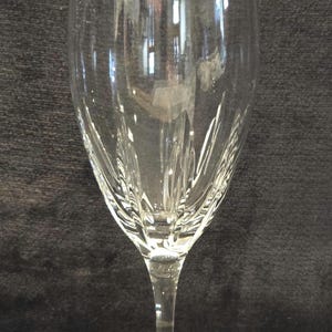 May include: A clear wine glass with a long stem and a wide bowl. The glass has a decorative etched pattern on the bowl. The glass is made of clear glass and is designed for serving wine.