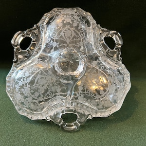May include: A clear glass serving dish with three sections and two handles. The dish is decorated with an etched floral pattern.