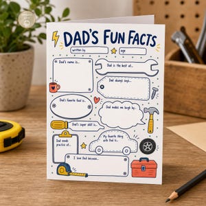Può includere: Un biglietto bianco con la scritta "DAD'S FUN FACTS" in blu e giallo. Il biglietto presenta spazi per inserire informazioni su un padre, con illustrazioni di una chiave inglese, un'auto e una cassetta degli attrezzi. Il biglietto è su una superficie di legno.