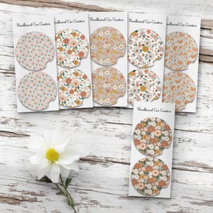 May include: A collection of hardboard car coasters with floral and butterfly patterns in various colors, including pink, orange, and yellow. The coasters are displayed on white cards, with the text "Hardboard Car Coasters" printed on them.