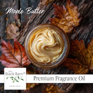 May include: A jar of maple butter fragrance oil with a swirl design, surrounded by autumn leaves. The text "Maple Butter" is at the top, and "Premium Fragrance Oil" is at the bottom. The Black Barn logo is in the lower left corner.