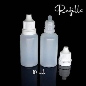 May include: Three clear plastic dropper bottles with white caps and the word "Refills" in cursive. The bottles are labeled "10 ml". The bottles are on a black background.