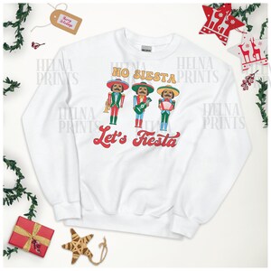 May include: White sweatshirt with a festive design featuring three cartoon figures in sombreros playing musical instruments. The text "No Siesta Let's Fiesta" is printed in red and white.