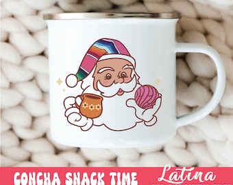Può includere: Tazza smaltata bianca con un'illustrazione di Babbo Natale con un cappello colorato e che tiene in mano una tazza e una pasticceria concha. La tazza ha un bordo argentato e un manico bianco. Il testo "CONCHA SNACK TIME" è in basso.