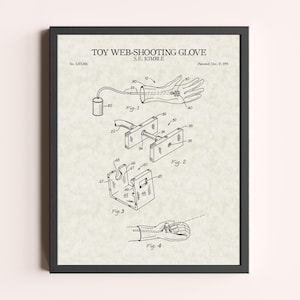 Peut inclure: Impression encadr&eacute;e d'un brevet de "Gant lanceur de toile" par S.E. Kimble. L'illustration en noir et blanc montre un gant avec des composants m&eacute;caniques, dont un r&eacute;servoir et un m&eacute;canisme de tir. L'impression est dans un cadre noir.