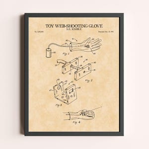 Peut inclure: Impression encadr&eacute;e d'un brevet de gant lanceur de toile, avec des sch&eacute;mas d&eacute;taill&eacute;s et le titre "TOY WEB-SHOOTING GLOVE" en haut. L'impression pr&eacute;sente des dessins techniques et des &eacute;tiquettes, avec un fond beige et un cadre noir.