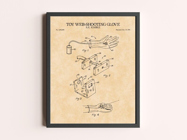 Peut inclure: Impression encadr&eacute;e d'un brevet de gant lanceur de toile, avec des sch&eacute;mas d&eacute;taill&eacute;s et le titre "TOY WEB-SHOOTING GLOVE" en haut. L'impression pr&eacute;sente des dessins techniques et des &eacute;tiquettes, avec un fond beige et un cadre noir.