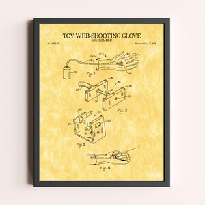Peut inclure: Impression encadr&eacute;e d'un brevet de "Toy Web-Shooting Glove" par S.E. Kimble, avec des sch&eacute;mas d&eacute;taill&eacute;s de l'appareil. L'impression a une esth&eacute;tique vintage avec un fond jauni et des illustrations &agrave; l'encre noire, encadr&eacute;e d'une bordure noire.