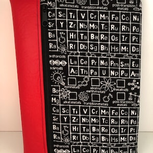 May include: A black and white periodic table print zippered pouch with a red leather-like spine. The pouch has a black zip and is designed for carrying items. The pouch is a science-themed accessory.