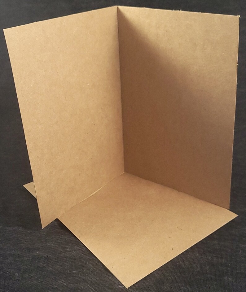 Op de afbeelding: Een blanco, bruine kaart gevouwen in de helft. De kaart is gemaakt van een getextureerd papier.