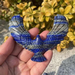 May include: A carved lapis lazuli eagle with outstretched wings. The eagle is a deep blue color with white veins running through the stone. The eagle is a popular symbol of freedom, strength, and power.