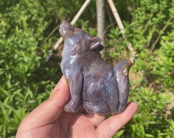 May include: A carved wolf figurine made of purple and grey agate. The wolf is howling with its head tilted back and its tail curled around its body.