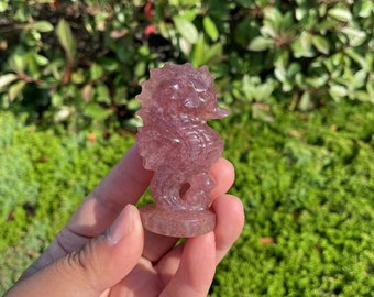 May include: A pink and white seahorse carved from crystal. The seahorse is standing on a small base.
